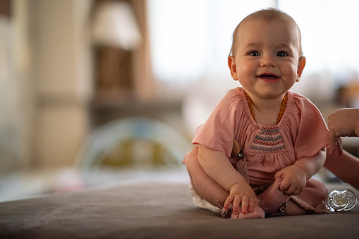 Portrait of a happy baby girl sitting on sofa in living room