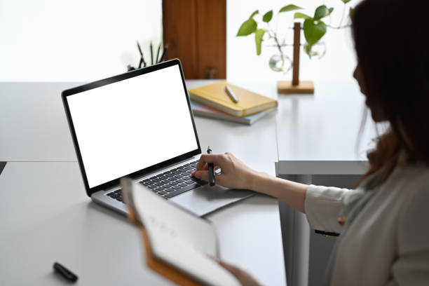 istock View over shoulder businesswoman holding notebook and using laptop at her office desk. 1409642641
