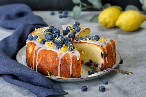 Lemon blueberry cake covered with sweet sugar icing, berries and lemon zest