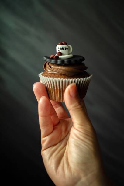 Chocolate cupcake in hand. Coffee decoration on top.