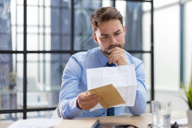 istock Handsome entrepreneur reading a letter from envelope in a desktop at office. 1409650035