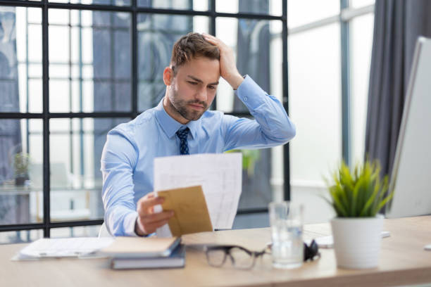 istock Handsome entrepreneur reading a letter from envelope in a desktop at office. 1409650575