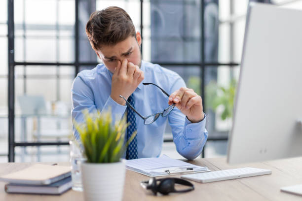 istock Handsome young business man with closed eyes touching face with hands while sitting on working place in office 1409650668