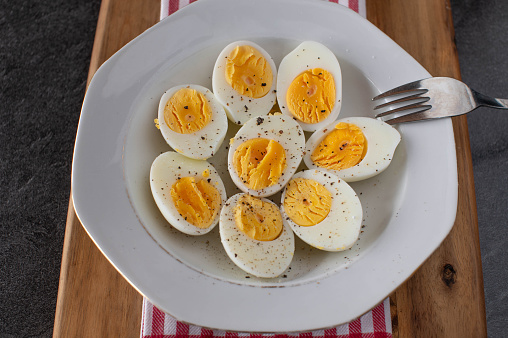 A plate with fresh and homemade boiled eggs. Seasoned with ground pepper and salt isolated on a table. Top view