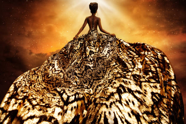 modemodell im goldenen fliegenden kleid, das licht anschaut. afro style frau in gold long gown flatternd auf wind rückansicht. exotische tänzerin mit seidenstoff über art fantasy hintergrund - evening wear stock-fotos und bilder