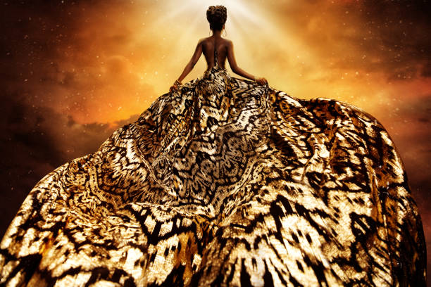 fashion model in golden flying dress looking away at light. afro style woman in gold long gown fluttering on wind rear view. exotic dancer with silk fabric over art fantasy background - female stripper imagens e fotografias de stock