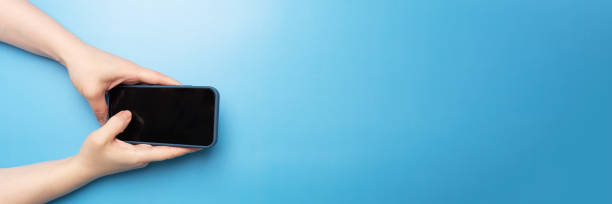 istock mobile app banner, female hand with phone on blue background top view 1409657561