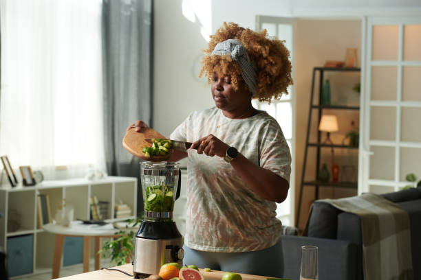 woman making vitamin cocktail at home - appliance living room domestic room lifestyles imagens e fotografias de stock