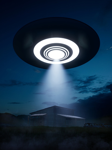 3d render. The ufo froze in the air at night, illuminating an abandoned farm with a beam of light.