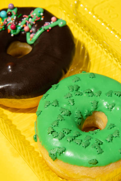 istock Two donuts chocolate and green on a yellow background in a box close-up. Studio vertical photo. 1409661232
