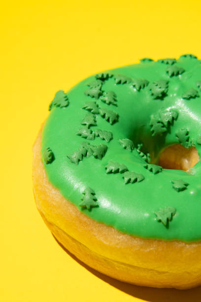 istock Green donut on a yellow background from the side, vertical photo. Studio shooting. 1409661275