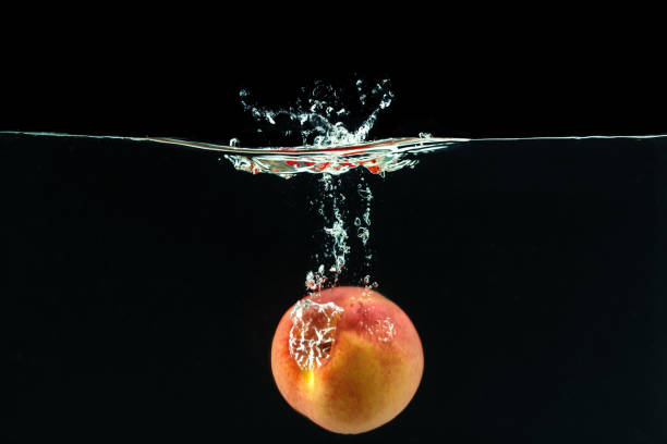 Peach dropped into water with bubbles