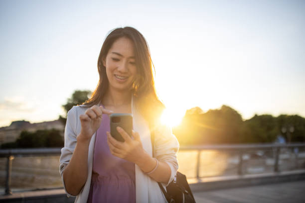 istock Woman Japanese ethnicity working on mobile phone, while walking through city 1409663084