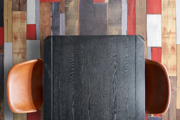Part of Patterned and textured black wooden table and chairs on colored parquet