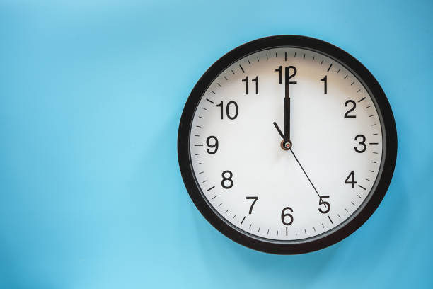 istock Classic black and white analog clock on blue background at Twelve o'clock with copy space 1409664537