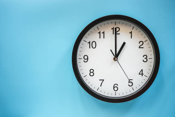 istock Classic black and white analog clock on blue background at One o'clock with copy space 1409664541