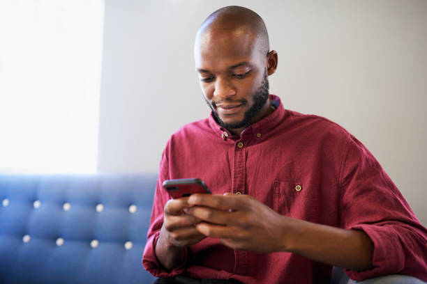 istock A Black man sits on a blue sofa and uses his cellphone 1409668542