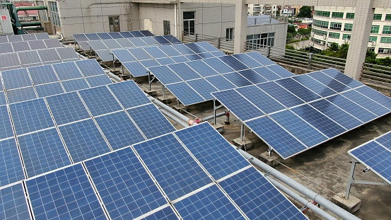 solar panels and wind turbines generating electricity in power station green energy renewable with blue sky background