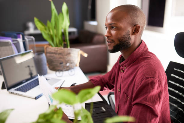 istock A Black man sits at his office desk with notes and laptop 1409669567