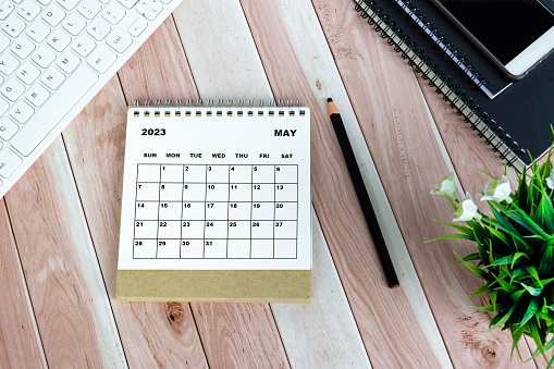 Calendario blanco de mayo de 2023 sobre escritorio de madera con papelería de oficina. photo