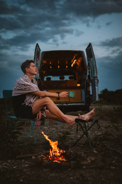istock Young man relaxes by the fire near the mini van 1409671537