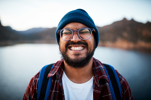An attractive man pulls a silly grin on a hiking trip by a lake. High quality photo