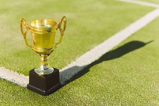 Golden prize cup for winner of competition on tennis court lawn