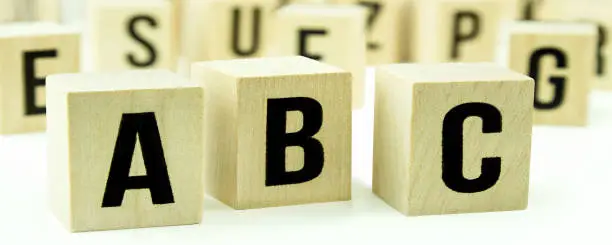 A B C letters on wooden cubes against white background