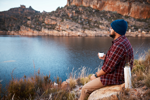 A man closes his eyes and enjoys the peace while drinking coffee on mountain camping trip. High quality photo