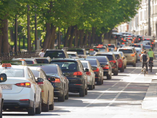 Traffic on the road in the Moscow in summer Moscow, Russia - May 17, 2019: Cityscape. City center in spring sun day. Big traffic. Street is filled out by cars. Backs, rear view. Narrow street. Two cyclists on the bycicle lane. Lifestyle concept traffic jam stock pictures, royalty-free photos & images