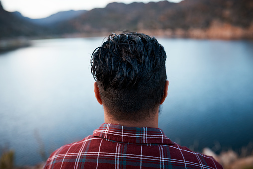 The back of a man's head while he admires the lake view on camping trip in the mountains. High quality photo