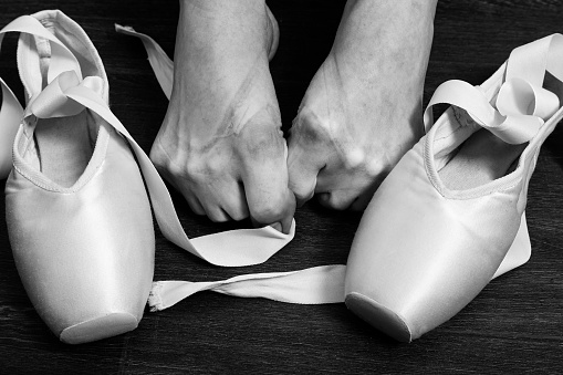 female ballerina feet with pointes after dance on a wooden floor closeup monochrome image