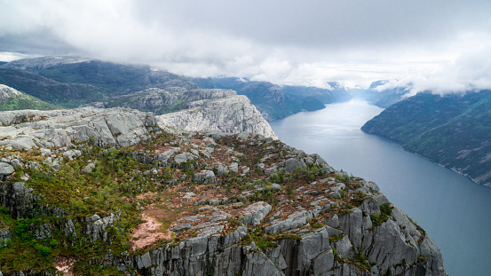 Lysefjord between high mountains on a cloudy day passing Preikestollen