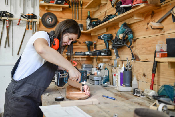 istock Female Carpenter Drilling Hole In Plank 1409689417