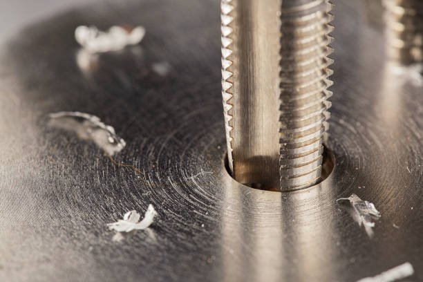 istock Thread tap drill steel billet with drill bit on background. Working cutter. 1409691603