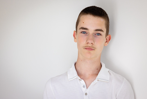 Portrait of 13 year arrogant old teenage Caucasian boy with blue eyes,  mole on forehead