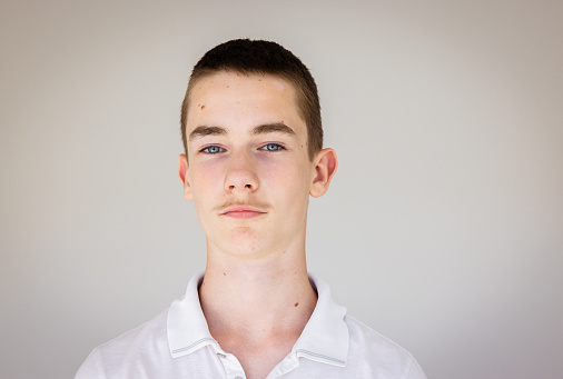Portrait of 13 year arrogant old teenage Caucasian boy with blue eyes,  mole on forehead