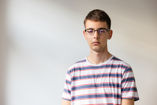 Portrait of Caucasian teenage boy, in striped T-shirt, wear eyeglasses