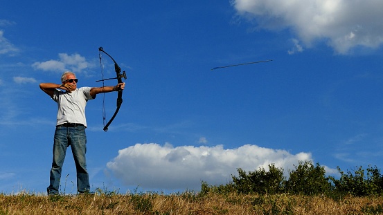 Archery training of a man in the countryside under blue sky