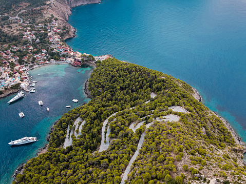 aerial shot drone of ASSOS village, cephalonia island, greece. view of amazing emerald sea and green hills, colorful houses and some sail boats and cruisers