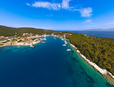 aerial panoramic drone photography of Fiskardo village,cephalonia island, greece with a green coastline and some sail boats. in a sunny day with emerald sea en blue sky