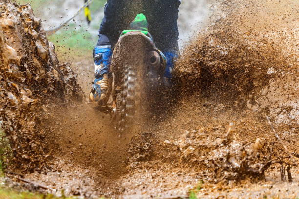 istock enduro rides through the mud with big splash,driver splashing mud on wet and muddy terrain,Motocross racer in a wet and muddy terrain covering the driver completely. 1409697864