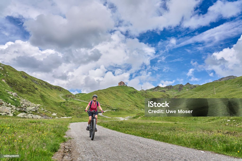 senior woman on electric bicycle in Silvretta mountains, Tirol, Austria nice active senior woman riding her electric mountain bike in the silvretta mountain range near Gaschurn, Tyrol, Austria Electric Bicycle Stock Photo