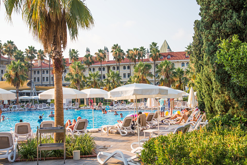 Turkey, Antalya, Lara beach - July 9, 2022:  Lots of sun beds by the pool in Lara beach Topkapi palace hotel. People relaxing by the pool