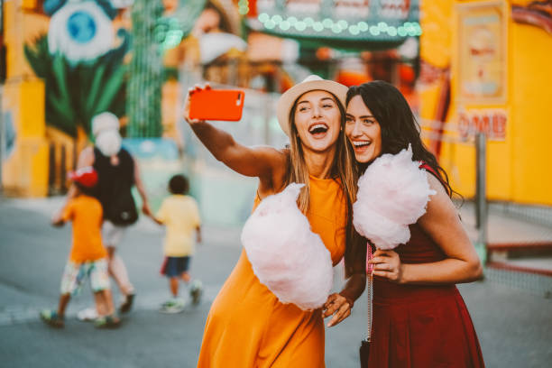 frauen im freizeitpark rosa zuckerwatte essen und nehmen selfie/vlogs - vacations two generation family caucasian friendship stock-fotos und bilder