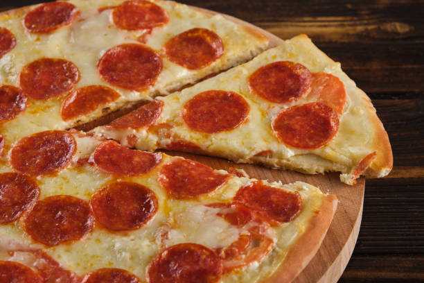 istock Pepperoni pizza on a wooden background close-up 1409705994