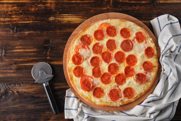 istock Pepperoni pizza on a wooden background top view 1409706014