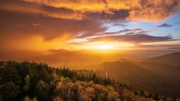 the sun shines through a gap in the cloudy sky and colours a departing thunderstorm in golden shades - forest black forest sky night imagens e fotografias de stock