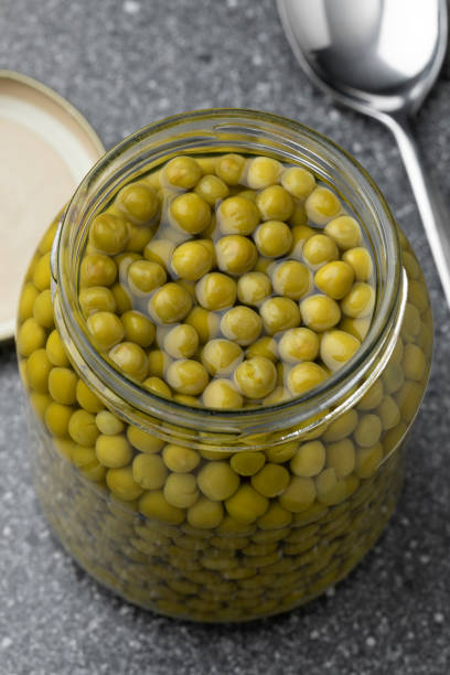 istock Glass jar with small green peas close up 1409708118