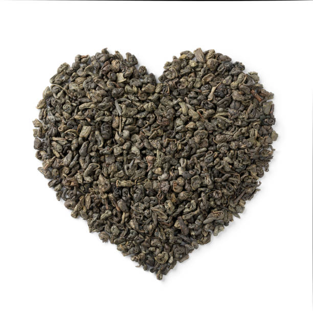 folhas de chá de pólvora secas em corações formam de perto em fundo branco - heart shape isolated isolated on white tea leaves - fotografias e filmes do acervo